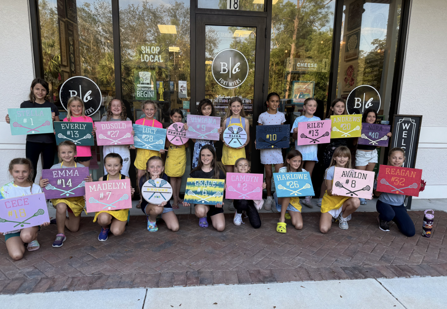 Storm players holding hand-painted lacrosse signs outside Board & Brush Fort Myers